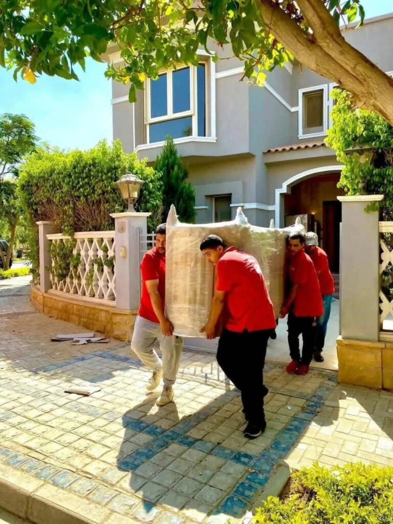 فريق شركة الحمد أثناء حمل قطعة أثاث متغلّفة أمام فيلا - شركة الحمد لنقل الأثاث